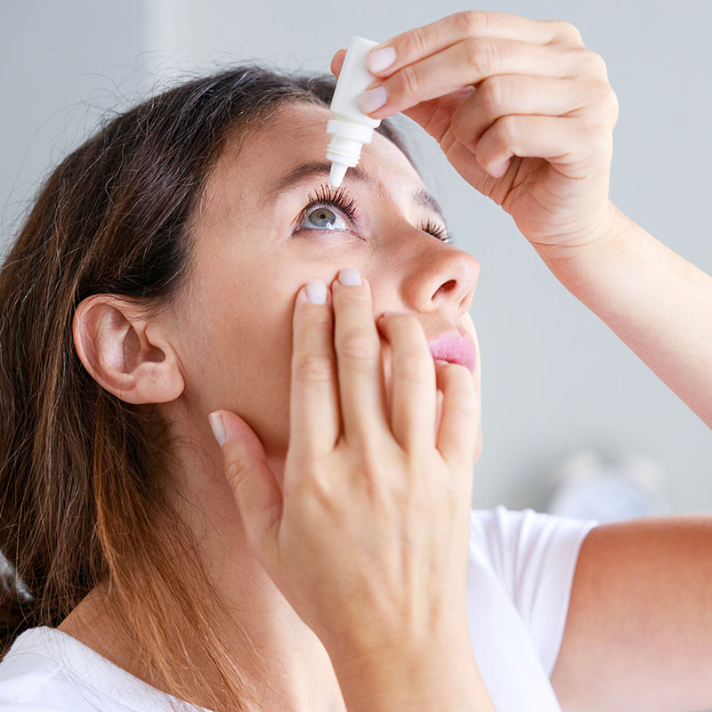 Woman carefully placing eye drops in her eye